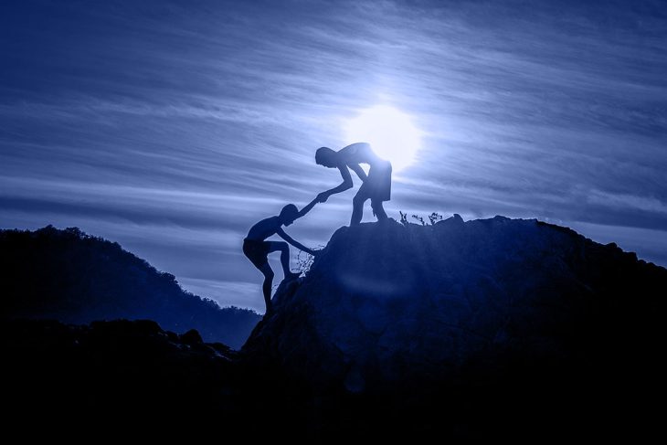A person helping another person climb a mountain.